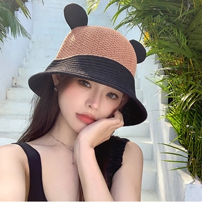 Close-up of dual-tone fisherman hat with cute ears against a tropical plant background