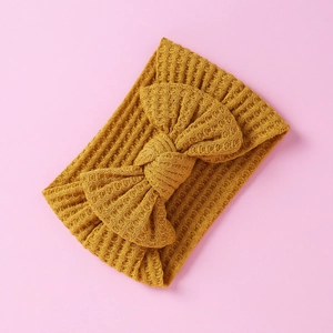 Macro detail of mustard yellow waffle knit baby headband with a decorative large bow