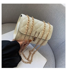 Detail of off-white quilted chain bag with gold metal lock and textured leather finish