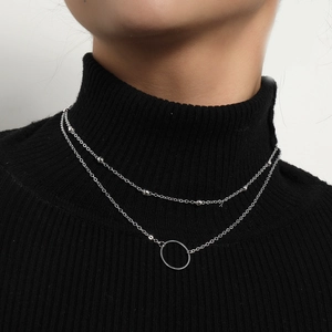 Double-layered silver necklace with bead chain and round pendant worn on black clothing
