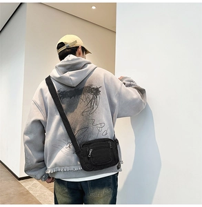 Close-up of black washed denim crossbody bag on model wearing a grey hoodie