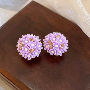 Gros plan de boucles d'oreilles fleurs violettes avec strass sur socle en bois
