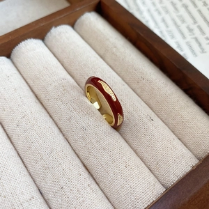 Macro shot of retro red enamel 14k gold plated ring on a beige linen jewelry display