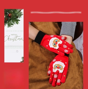 Close-up of red knitted Christmas gloves with Santa embroidery and touchscreen fingertips