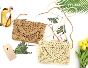 Detail of hand-woven straw crossbody bag with decorative fringe and braided shoulder strap