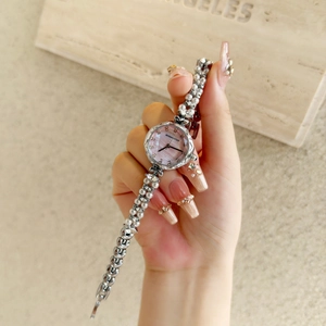 Detail of luxury women's watch with pearl bracelet strap and purple mother-of-pearl dial