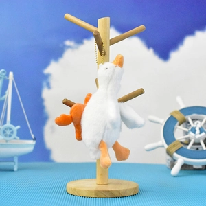 Cute plush white goose keychain pendant hanging on a natural wooden display stand