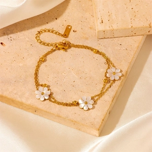 Gros plan du bracelet doré à double couche avec fleurs en nacre sur une pierre