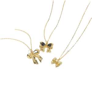 Three elegant gold bow pendant necklaces featuring smooth, black stone, and heart details