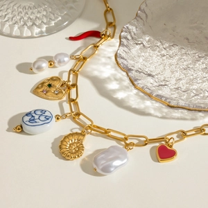Gold ocean necklace with ceramic charms and pearls on a neutral background