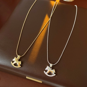 Gros plan de pendentifs cheval à bascule or et argent sur surface en cuir brun