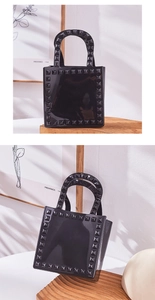 Detailed macro view of black jelly tote bag with silver rivets and polished PVC texture