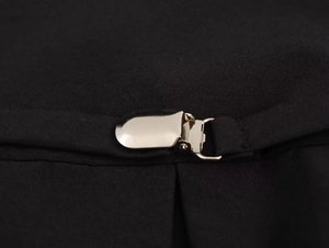Detailopname van een zilveren metalen clip op zwarte stof met fijne weefstructuur