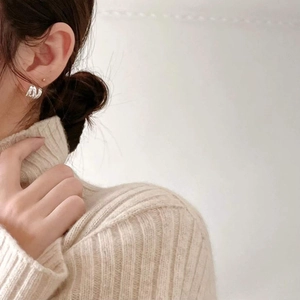 Minimalist 925 sterling silver wave hoop earrings on model with cozy knit sweater