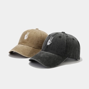 Close-up of vintage washed cotton baseball caps with skeletal peace hand embroidery