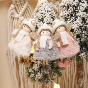 Detailed view of plush angel ornaments with gold wings on a snowy Christmas tree