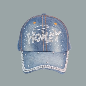 Detailed view of HONEY rhinestone embellishments on a blue denim baseball cap