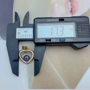 Detailed measurement of a gold heart-shaped evil eye pendant using digital calipers at 17.3 mm