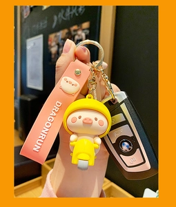 Detailed close-up of a cute pink pig doll on a yellow motorcycle keychain accessory