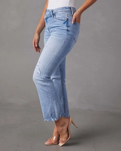 Dettaglio dei jeans azzurri con strappi, orli sfilacciati e texture in denim lavato vintage