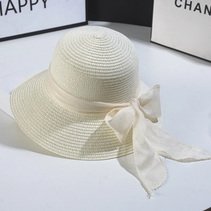 Detailed texture of cream straw sun hat featuring a large elegant ribbon bow decoration