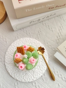Close-up of a dessert-shaped scented candle with waffle and cream details on lace