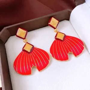Elegant red fan-shaped fishtail earrings with golden relief on jewelry box