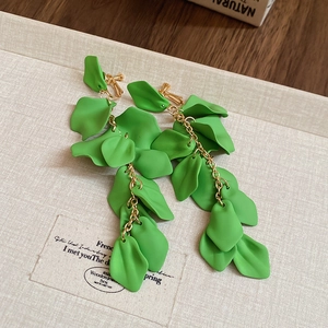 Detail of green rose petal tassel clip-on earrings with gold chains in a jewelry box