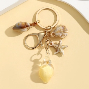 Nautical theme keychain with conch shells and starfish pendants on a golden metal ring