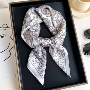Detailed view of white paisley silk scarf folded in a premium black gift box set
