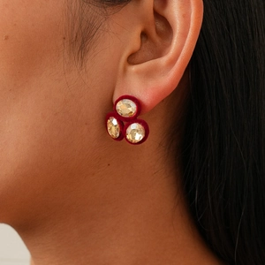 Macro side view of a model wearing burgundy flocked earrings with three clear rhinestones