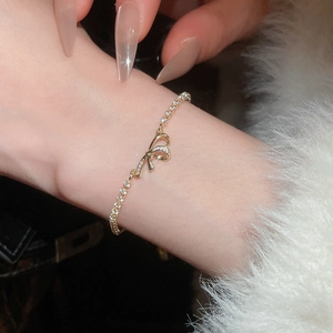 Detail of elegant gold bow bracelet with cubic zirconia on a model wrist