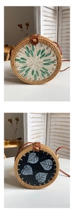 Detailed view of handmade round rattan bags with floral patterns and leather straps