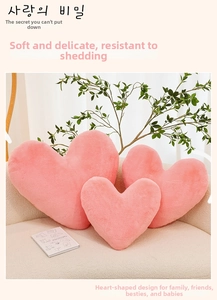Detailed view of three pink heart-shaped plush pillows in various sizes on a sofa