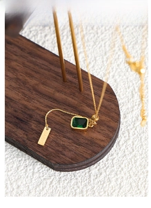 Detailed shot of emerald zircon rectangle pendant and BABY tag on gold chain