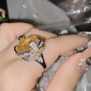 Detailed view of an 18k gold plated ring featuring a large yellow gemstone and floral design