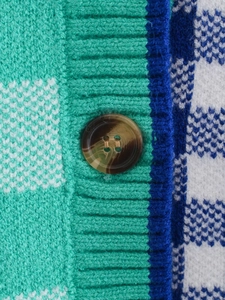 Detail of a brown marble button on a green and blue checkerboard knit cardigan