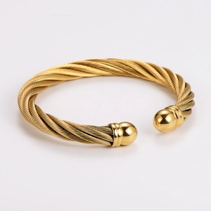 Macro detail of golden stainless steel cable wire bracelet with polished sphere ends