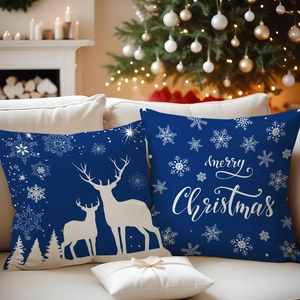 Close-up of blue Christmas pillowcases with white reindeer and snowflake prints on a sofa