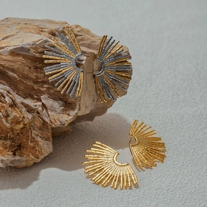 Minimalist sunflower earrings in gold and silver finish on natural stone background
