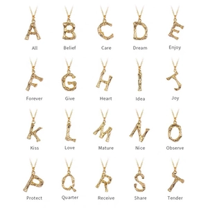Détail de colliers lettres en or 316L avec texture bambou sur fond blanc épuré