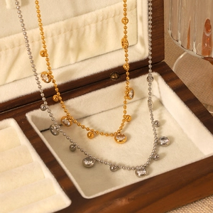 Elegant gold and silver beaded tassel necklaces with zircon stones on a velvet jewelry box