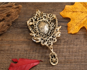 Macro shot of vintage bronze water drop brooch with skull charm on textured wood surface