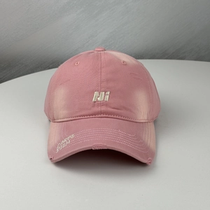 Distressed pale pink cotton baseball cap with embroidered letters and wide curved brim