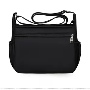 Detail view of the back of a black nylon shoulder bag with a zipper pocket and side pouches
