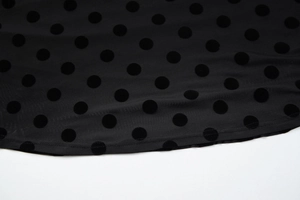 Detailed close-up of black mesh fabric with flocked polka dots and precise stitching