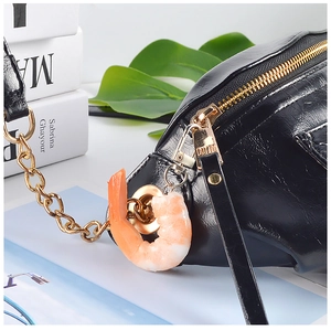 Detail van een zwarte crossbodytas met een realistische PVC-garnaal voedsel hanger