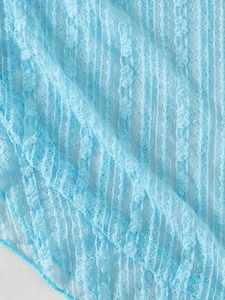 Vue détaillée de la dentelle florale bleu clair avec rayures verticales et texture filet