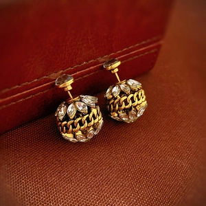 Détail macro de boucles d'oreilles boules dorées vintage avec zircons et texture chaîne