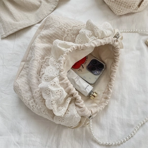 Detailaufnahme der Spitzen-Beuteltasche mit Kordelzug und einer Kette aus Perlen